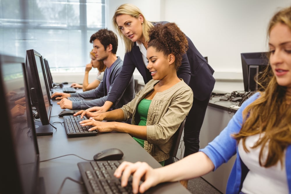 Attractive teacher helping her student in computer class at the university Attractive teacher helping her student in computer class at the university