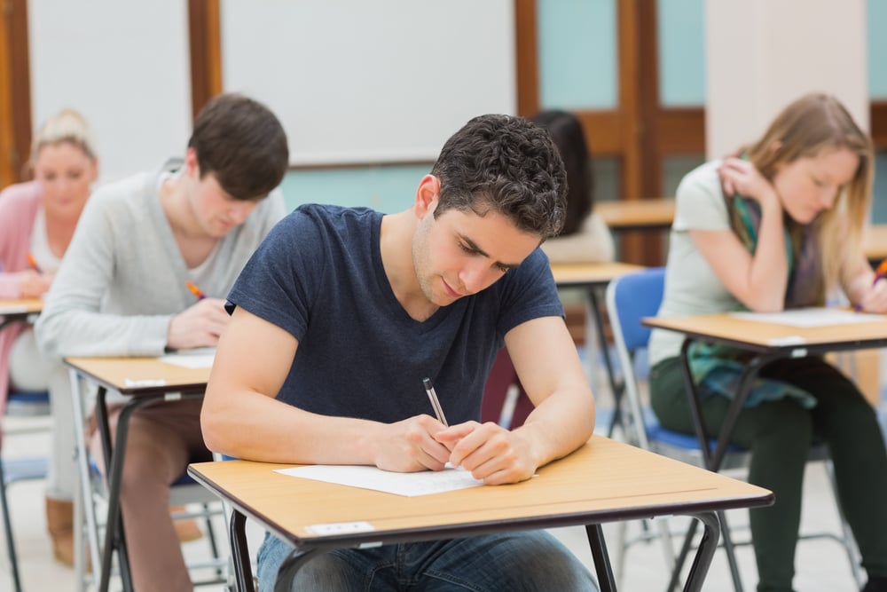 Students sitting in an exam hall doing an exam in university